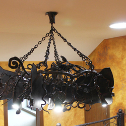 Detailansicht einer schmiedeeisernen Fledermaus ber einer Galerie  majesttischer Innenkronleuchter 