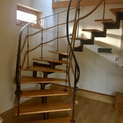 Forged helical staircase with railing, completed with ropes in the interior of afamily home in eastern Slovakia