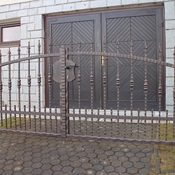 Schmiedeeiserner Zaun an einem Einfamilienhaus mit verdichteten Elementen im unteren Teil Schmiedeeiserner Zaun an einem Einfamilienhaus mit verdichteten Elementen im unteren Teil