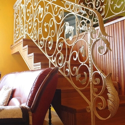 A hand wrought iron interior staircase railing - a white railing with gold-green patina A hand wrought iron interior staircase railing - a white railing with gold-green patina