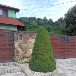 Handgeschmiedetes Tor und Pforte mit Holzfüllung als Zugang zu einem Einfamilienhaus Handgeschmiedetes Tor und Pforte mit Holzfüllung als Zugang zu einem Einfamilienhaus