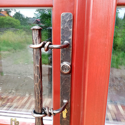 The hand-forged door handle on the entrance door with the logo UKOVMI