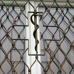 Handgeschmiedete Schlange auf einem Stab in der Mitte eines geschmiedeten Fenstergitters