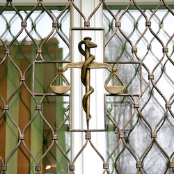 Geschmiedete Waage als Symbol der Pharmazie in einem Fenstergitter – Detailansicht