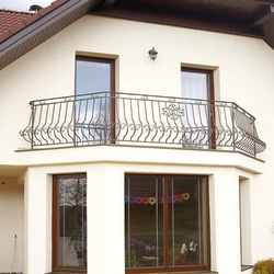 Geschmiedetes Geländer auf dem Balkon eines Einfamilienhauses – hochwertiges Geländer, oberflächlich bearbeitet für ein Exterieur Geschmiedetes Geländer auf dem Balkon eines Einfamilienhauses – hochwertiges Geländer, oberflächlich bearbeitet für ein Exterieur