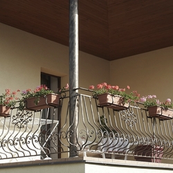 Geschmiedetes Geländer am Balkon eines Einfamilienhauses mit den Blumentopfhaltern Geschmiedetes Geländer am Balkon eines Einfamilienhauses mit den Blumentopfhaltern