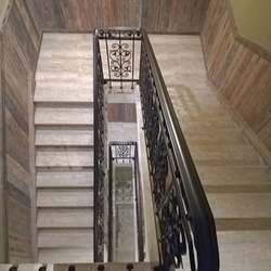 Pohled na schodišťové zábradlí shora - kované zábradlí v interiéru penzionu