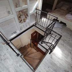 Pohled na vstup do podkroví - kované schodiště s dřevěnými stupačkami a zábradlím