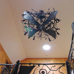 Schmiedeeiserne Fledermaus über einer Galerie – dominante Pendelleuchte in einer Hütte