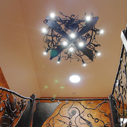 Luminaire d’intérieur – chauve-souris en fer forgé au-dessus d’une mezzanine – un lustre dominant – éclairage d’un chalet de montagne