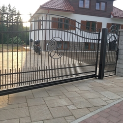 Schmiedeeisernes Schiebetor mit Pforte im einfachen Stil vor einem Einfamilienhaus Schmiedeeisernes Schiebetor mit Pforte im einfachen Stil vor einem Einfamilienhaus