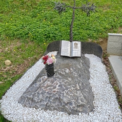 Pomník, který vypráví příběh - kříž ve tvaru olivovníku postavený na skále s otevřenou knihou, která píše o zesnulém